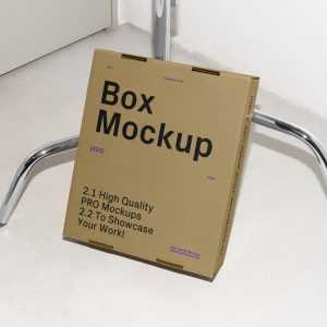 Free Cardboard Box Leaning Against the Tripod Mockup