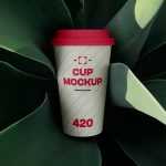 Free Coffee Cup Surrounded by Plant Mockup
