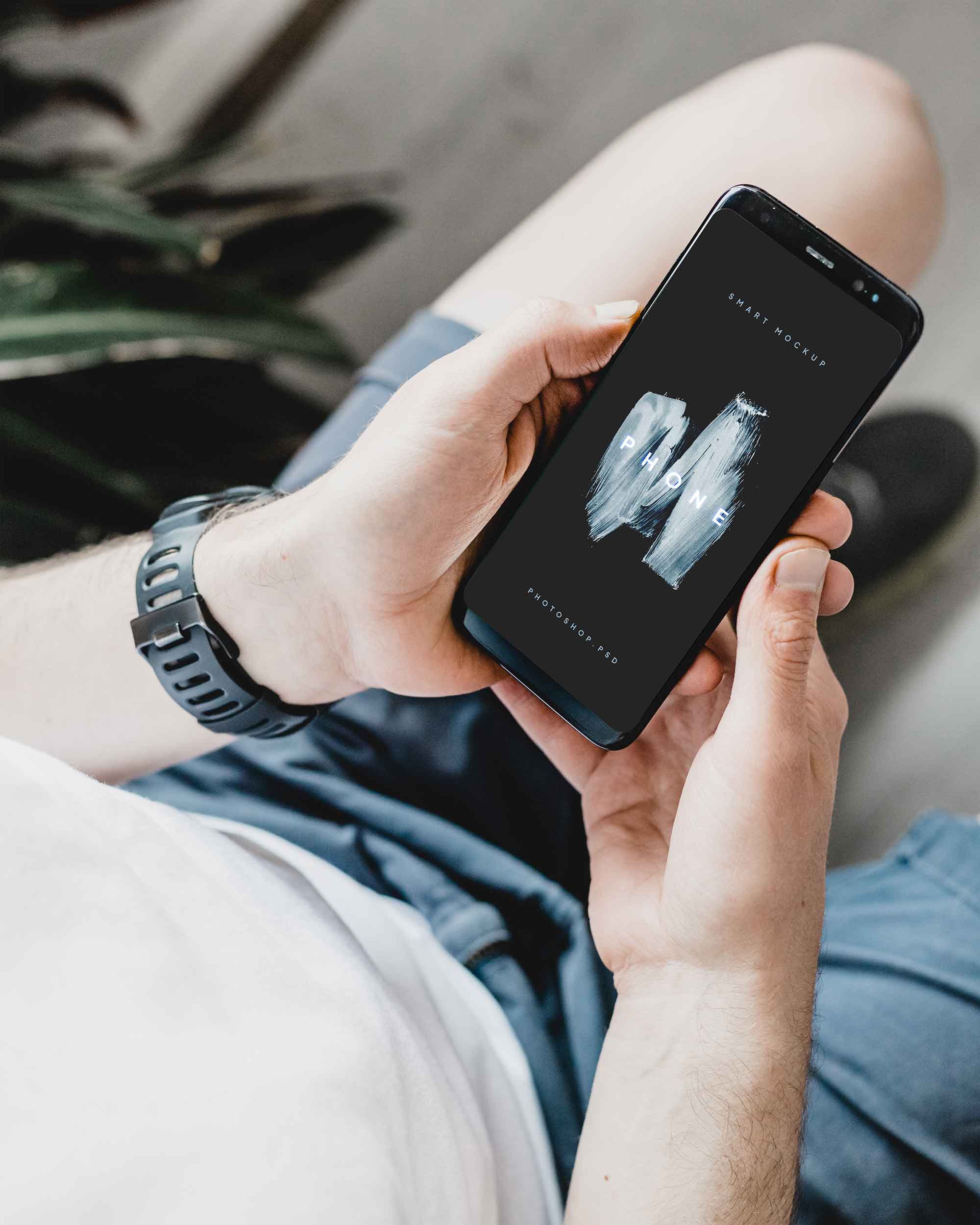 Free Man Watching his Android Phone Mockup PSD