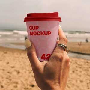 Free Paper Coffee Cup on the Beach Mockup